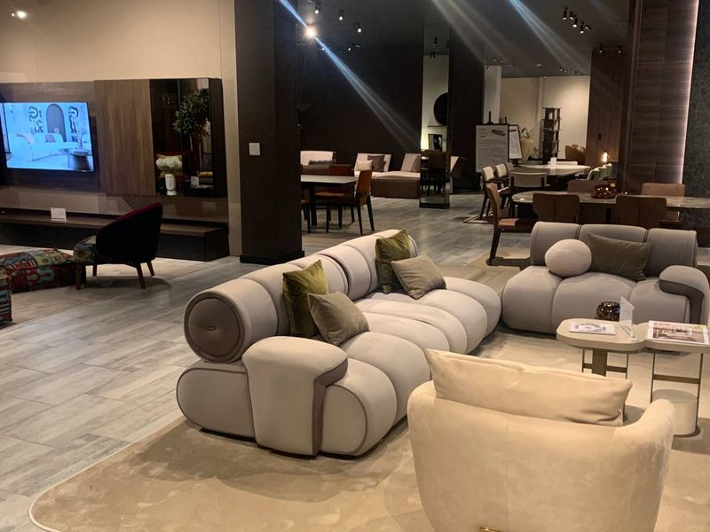 A spacious, modern retail showroom interior featuring tiled flooring, recessed ceiling lighting, and contemporary wall paneling.