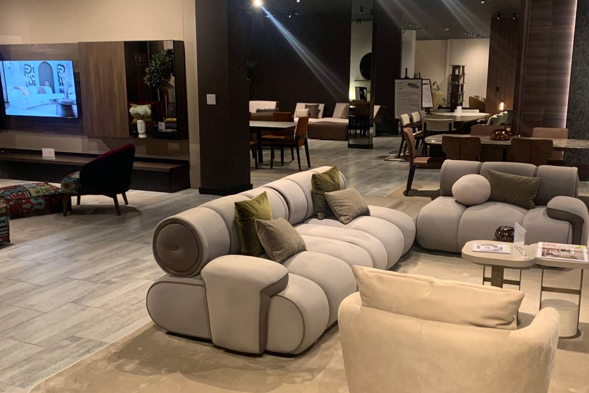 A spacious, modern retail showroom interior featuring tiled flooring, recessed ceiling lighting, and contemporary wall paneling.