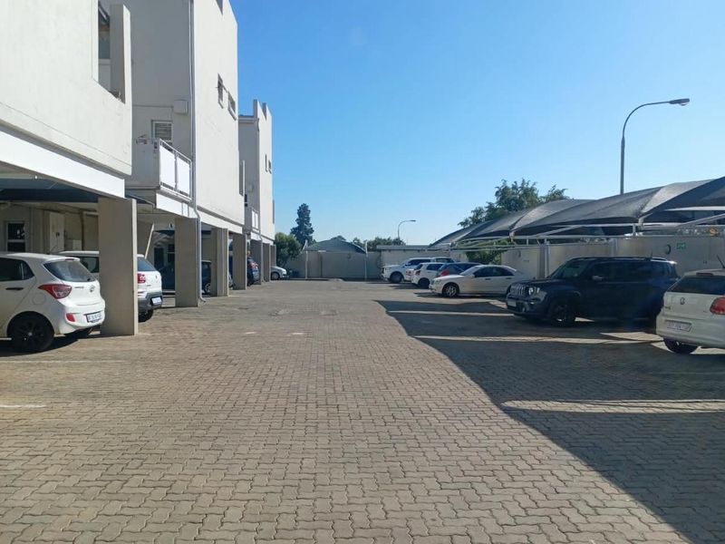 Exterior view of the apartment complex parking area featuring paved driveway and covered parking bays with shade cloth structures.