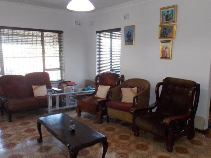A living room featuring tiled flooring, large windows with venetian blinds, and decorative cove cornicing.
