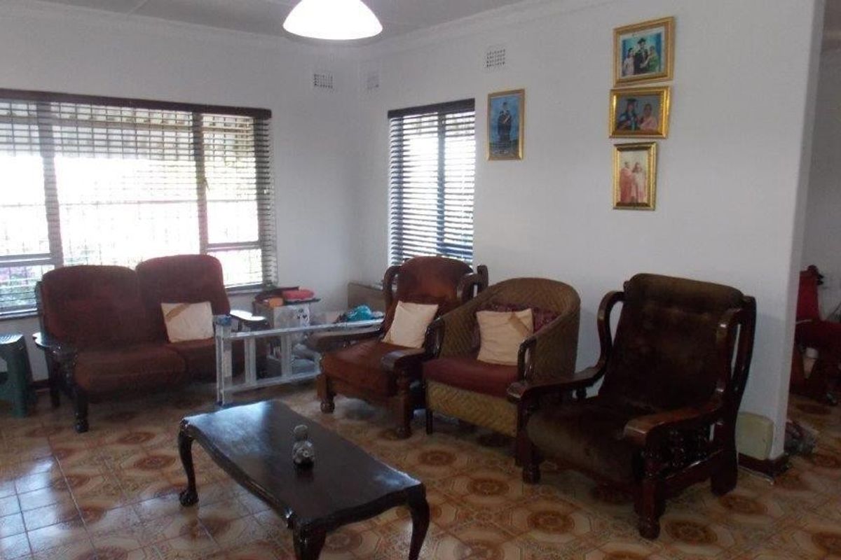 A living room featuring tiled flooring, large windows with venetian blinds, and decorative cove cornicing.