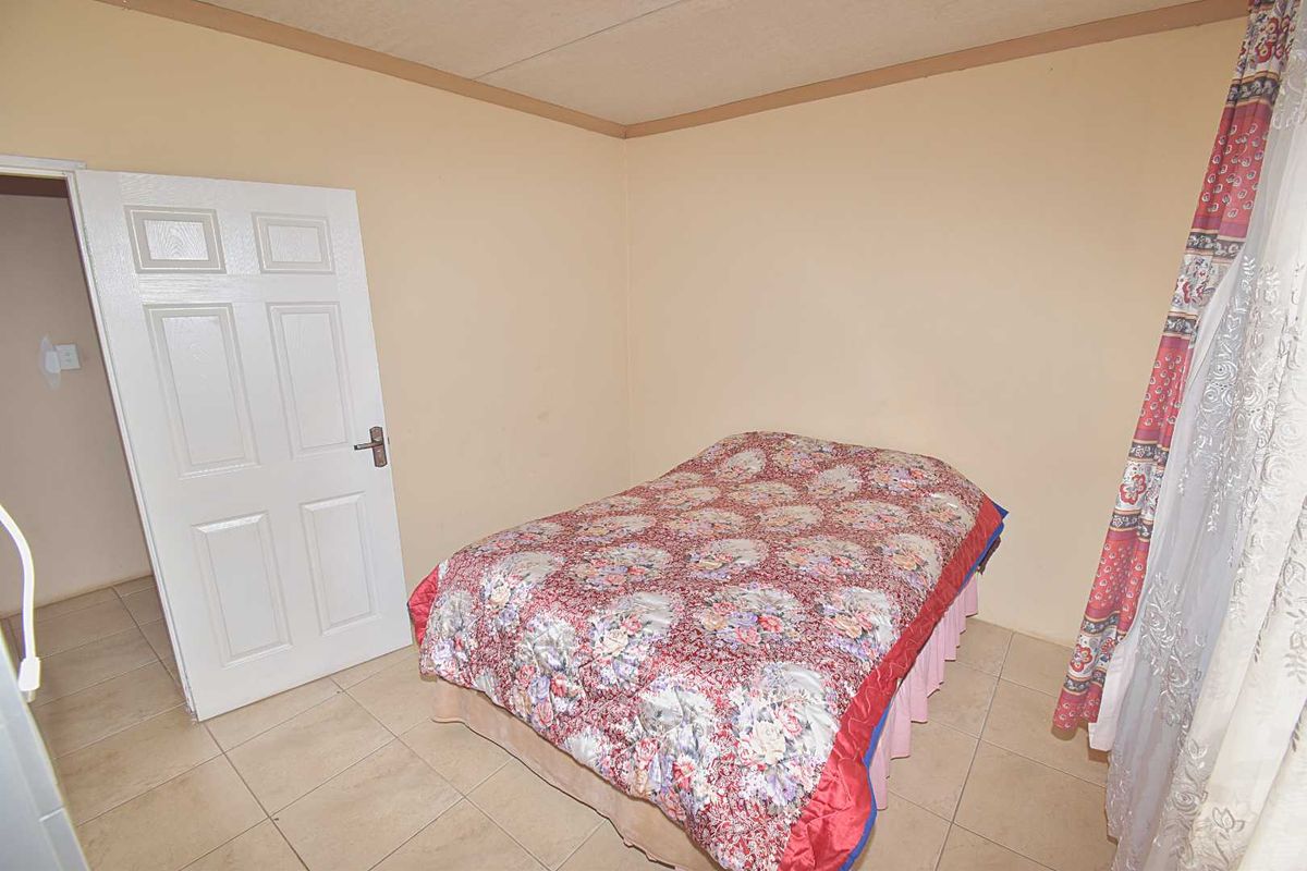 A compact bedroom featuring tiled flooring, a standard six-panel door, and neutral wall tones, offering a functional space ready for cosmetic updates.