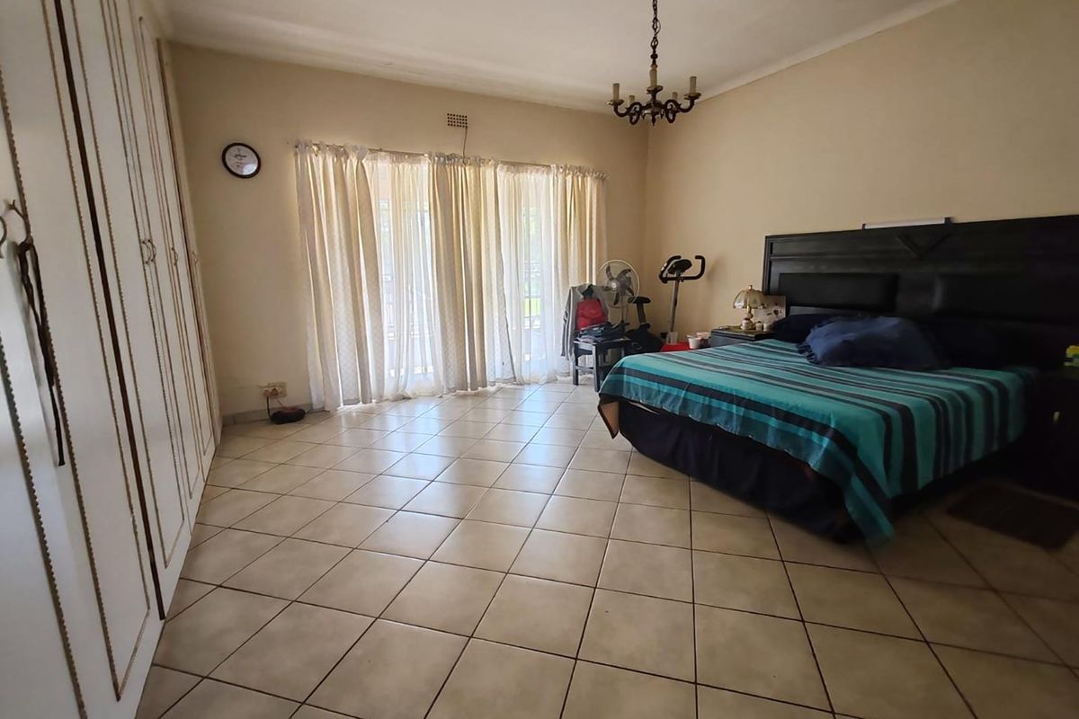 Spacious bedroom featuring tiled flooring, built-in cupboards, and sliding glass doors providing access to the outdoor area.