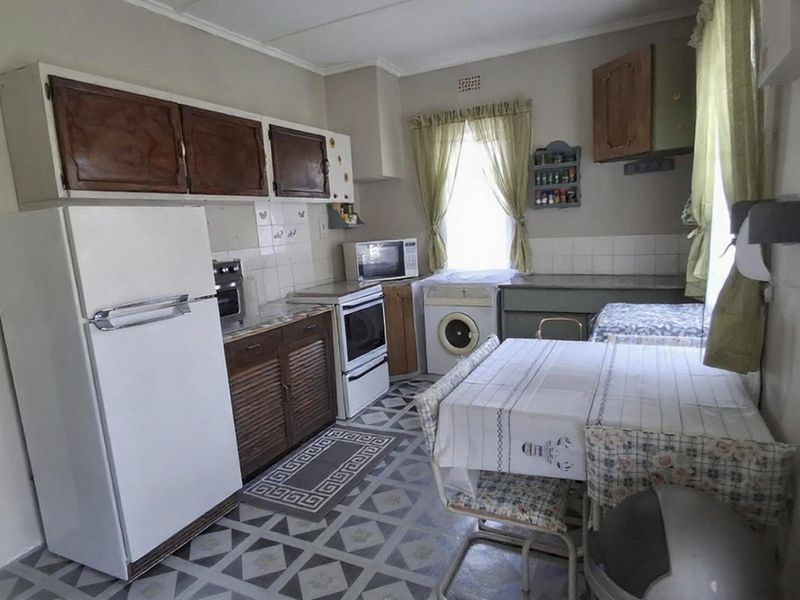 A functional kitchen featuring dated cabinetry, tiled flooring, and a tiled backsplash, offering potential for modernization and aesthetic updates.