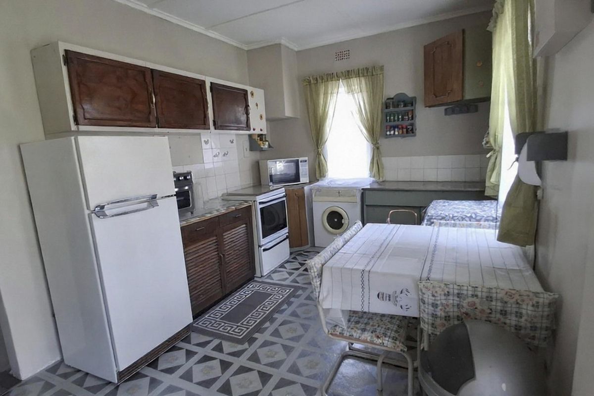A functional kitchen featuring dated cabinetry, tiled flooring, and a tiled backsplash, offering potential for modernization and aesthetic updates.