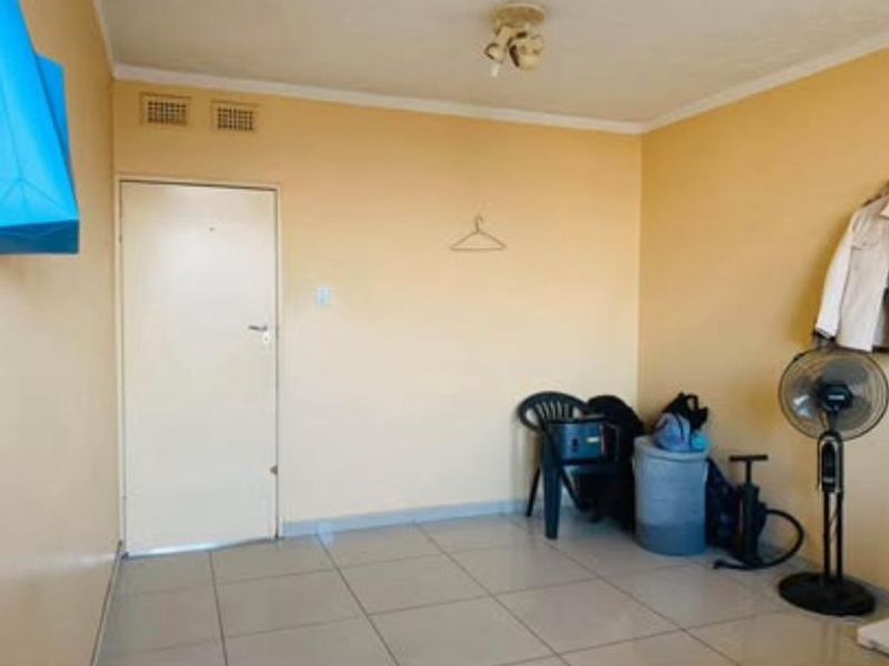 A simple, empty bedroom featuring tiled flooring and neutral wall paint, providing a blank canvas for potential interior design updates.