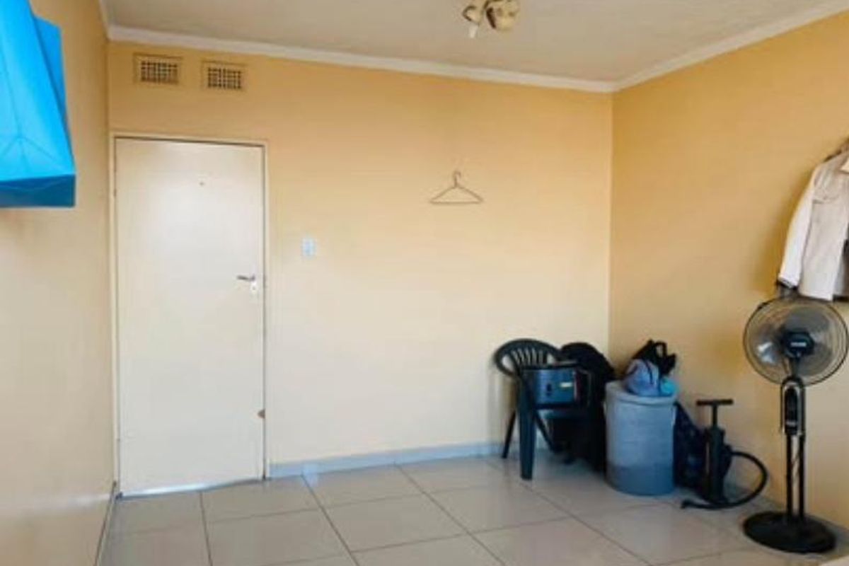 A simple, empty bedroom featuring tiled flooring and neutral wall paint, providing a blank canvas for potential interior design updates.