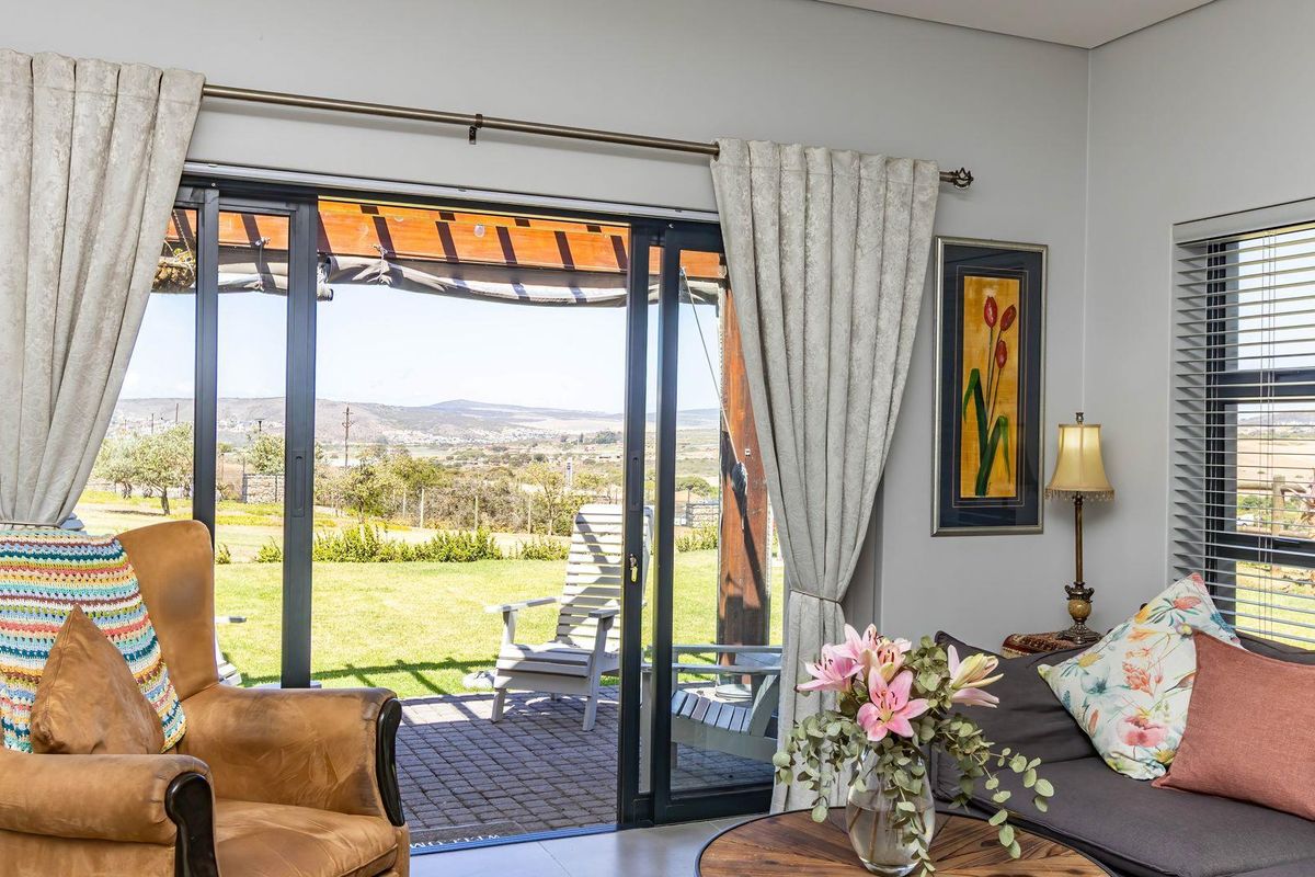 A bright living room featuring large sliding glass doors that open onto a paved patio with scenic landscape views.