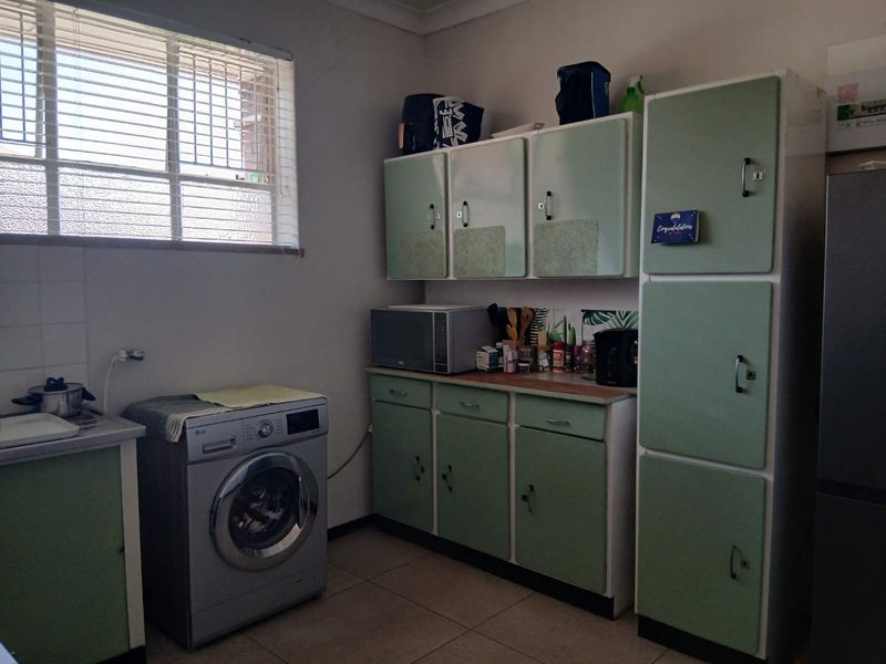 A functional kitchen area featuring vintage-style built-in cabinetry, tiled flooring, and dedicated plumbing connections for laundry appliances.
