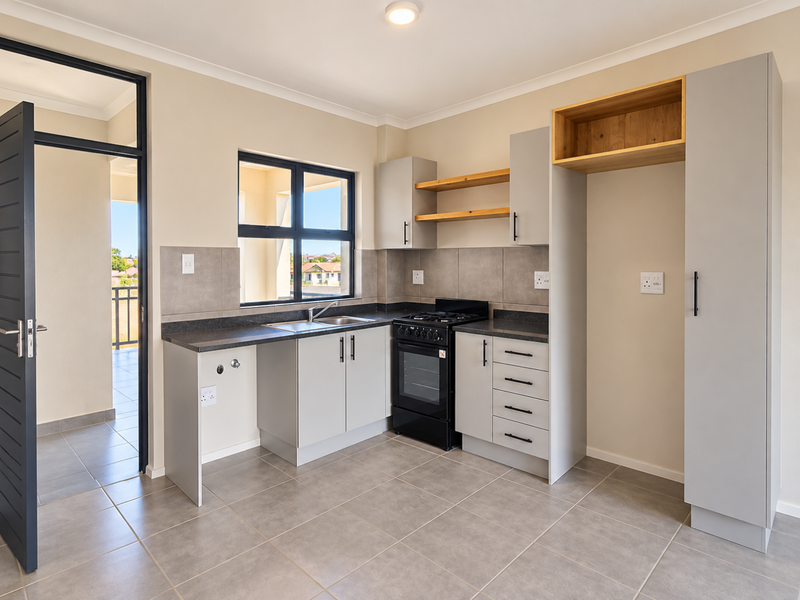 Modern kitchen featuring light grey cabinetry, stone countertops, open shelving, and a freestanding stove, with direct access to an outdoor balcony area.