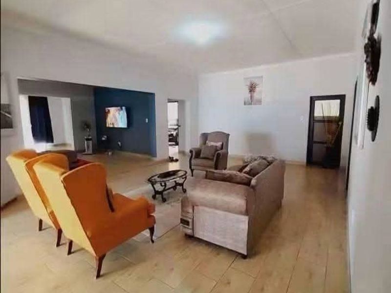 Spacious living area featuring light-toned tiled flooring and an open-plan layout connecting to an adjacent room.