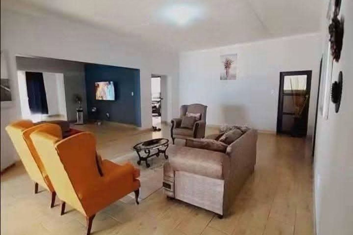 Spacious living area featuring light-toned tiled flooring and an open-plan layout connecting to an adjacent room.