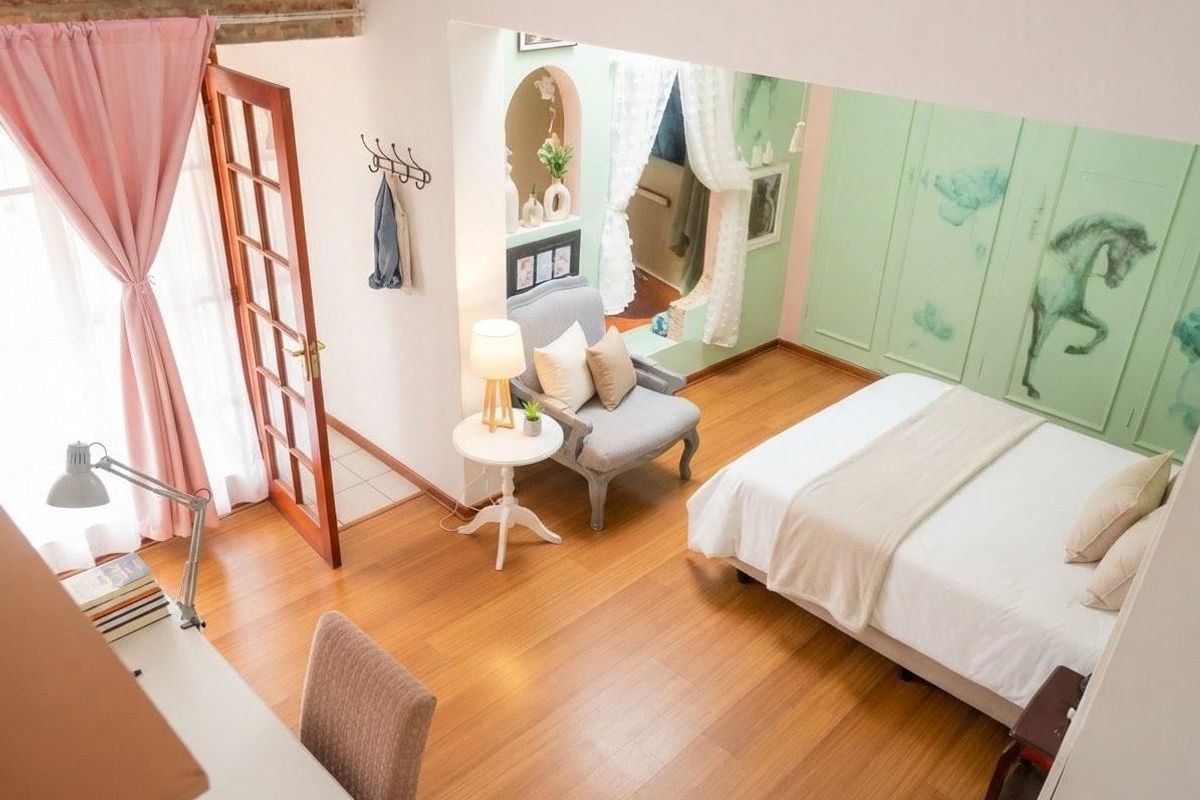 A bedroom featuring timber flooring, an exposed brick accent wall, and built-in wardrobe cabinetry with direct access to an outdoor area via a french door.