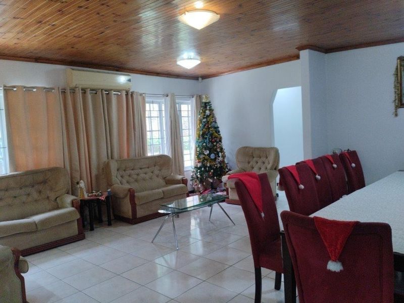 Spacious open-plan living and dining area featuring ceramic floor tiles and a warm timber tongue and groove ceiling.