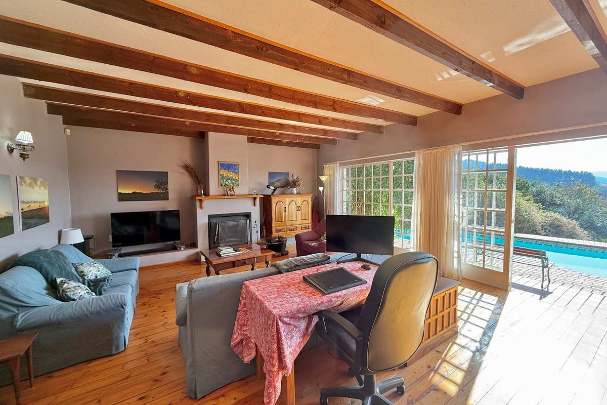 Spacious living room featuring exposed timber ceiling beams, hardwood flooring, and a built-in fireplace, with direct access to an outdoor patio and pool area.