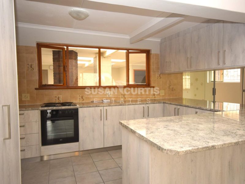 A functional kitchen featuring light-toned cabinetry, granite countertops, a tiled backsplash, and a freestanding oven, offering a clean and practical workspace.