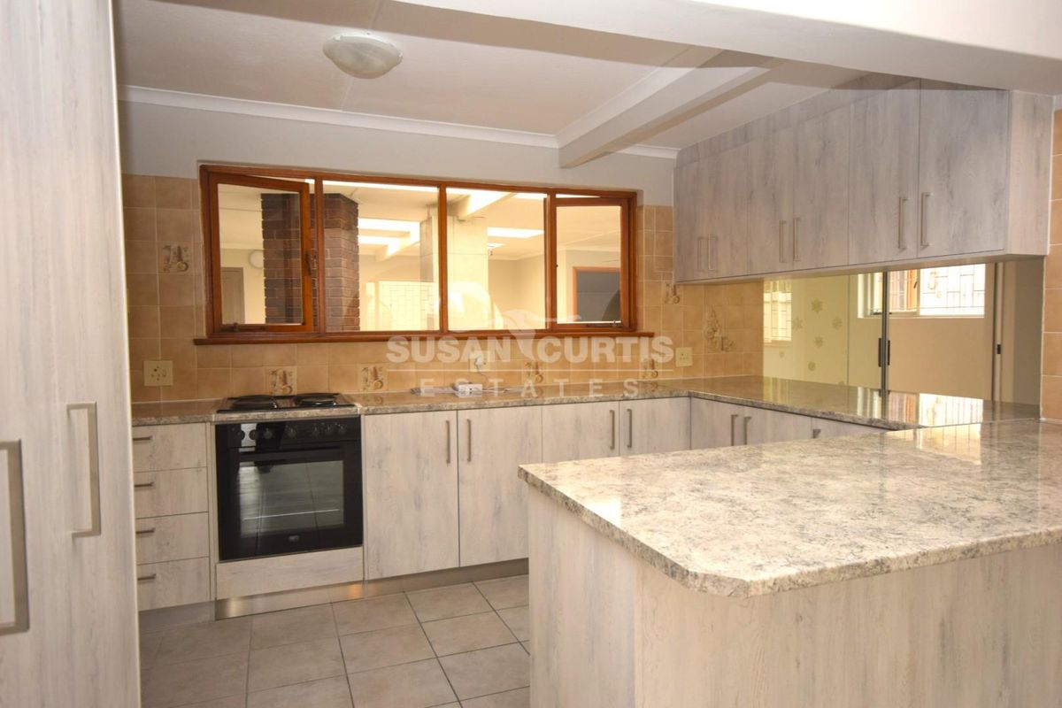 A functional kitchen featuring light-toned cabinetry, granite countertops, a tiled backsplash, and a freestanding oven, offering a clean and practical workspace.