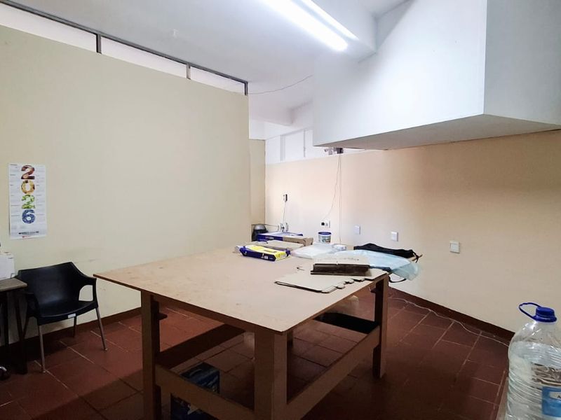 A functional office or workspace featuring tiled flooring, fluorescent lighting, and neutral wall finishes, suitable for various business or administrative uses.