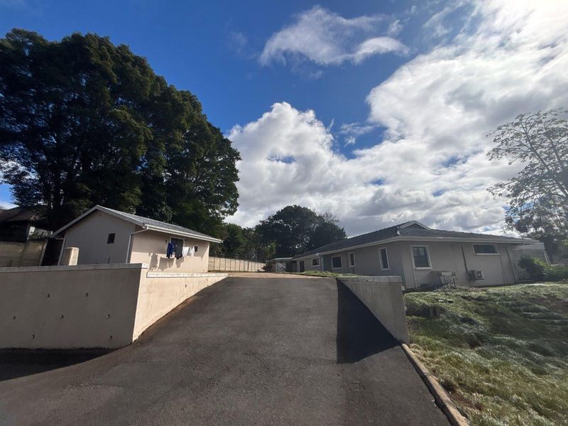 View of the property exterior featuring an asphalt driveway leading up to the main dwelling and a secondary structure with a pitched roof.