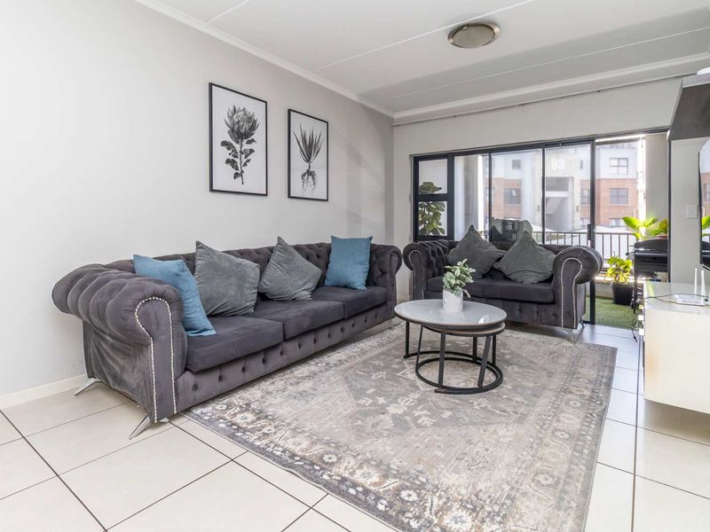 A bright living room featuring tiled flooring and a large sliding glass door that provides access to an outdoor balcony area.