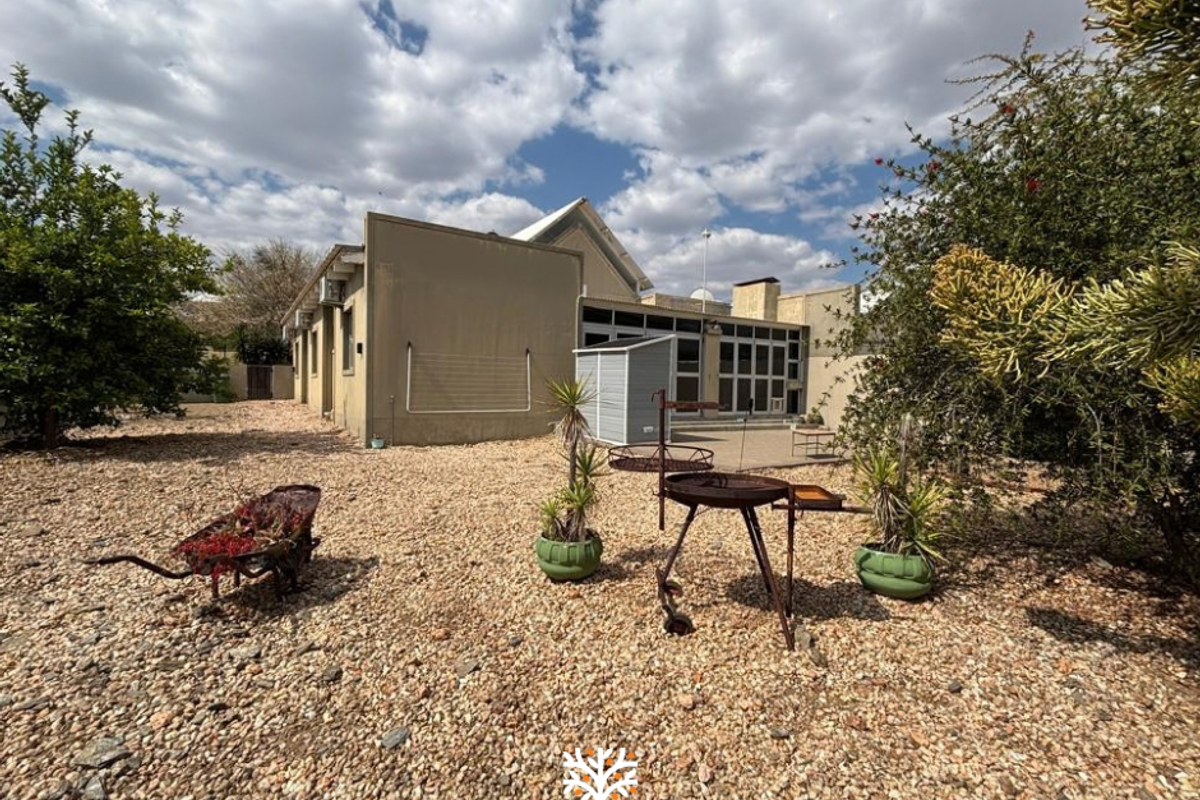Rear view of the property featuring a low-maintenance gravel garden, paved patio area, and established landscaping.
