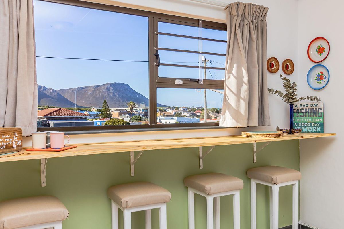A bright living area featuring a built-in breakfast bar positioned under a large window with scenic mountain and neighbourhood views.