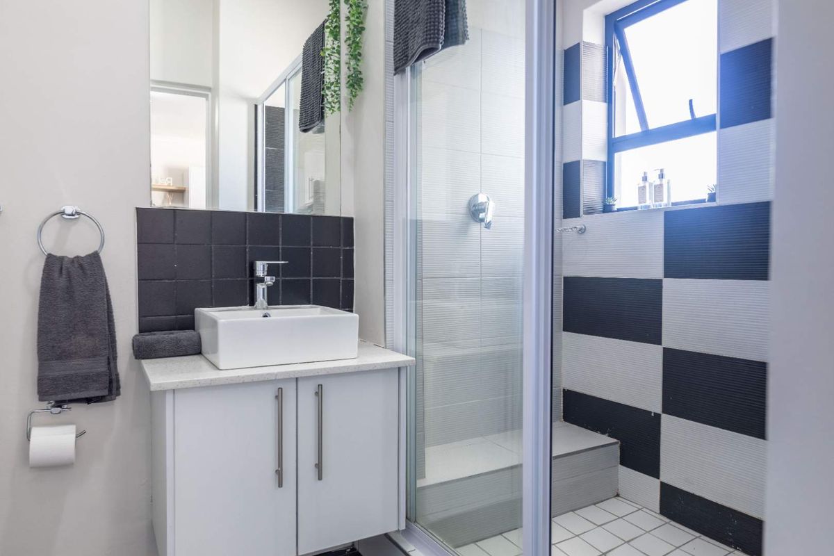 Modern bathroom featuring a vessel sink vanity, glass-enclosed shower, and striking black and white tiled accents.
