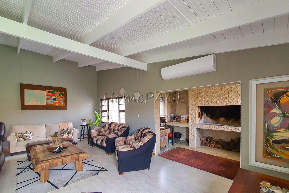 Spacious living room featuring a vaulted timber ceiling, split-system air conditioning, and a built-in stone fireplace with integrated prep area.