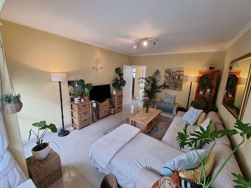 A comfortable living room featuring neutral tiled flooring and a central ceiling spotlight fixture, providing a functional and well-lit space.