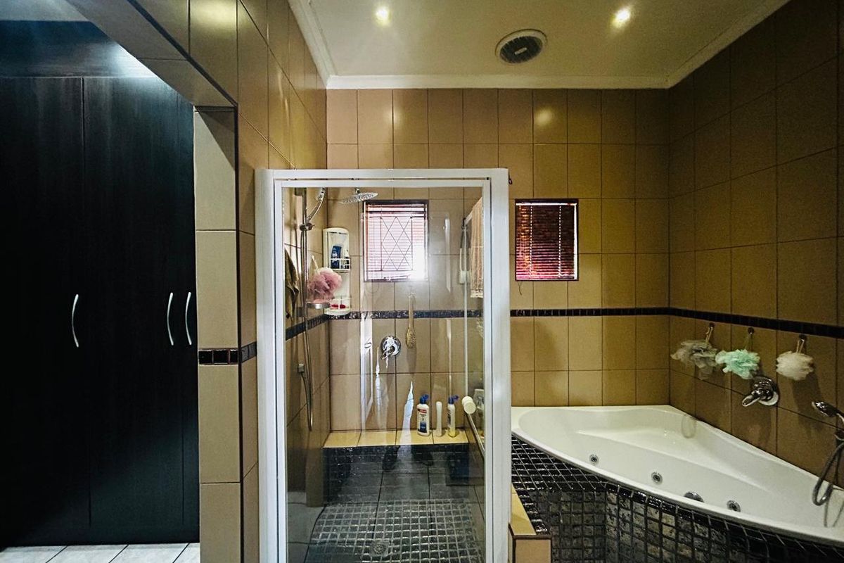 Bathroom featuring a corner spa bath, separate glass-enclosed shower, and full-height wall tiling.