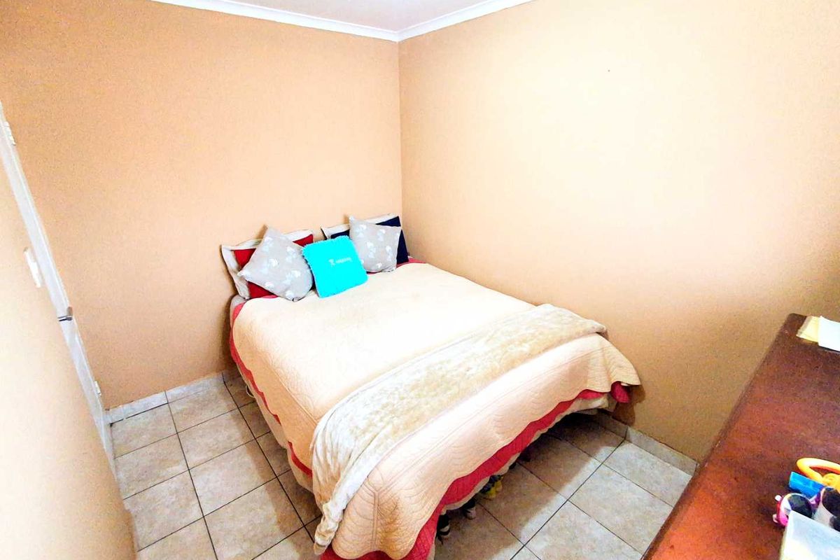 A compact bedroom featuring tiled flooring and neutral wall finishes, providing a functional sleeping space.