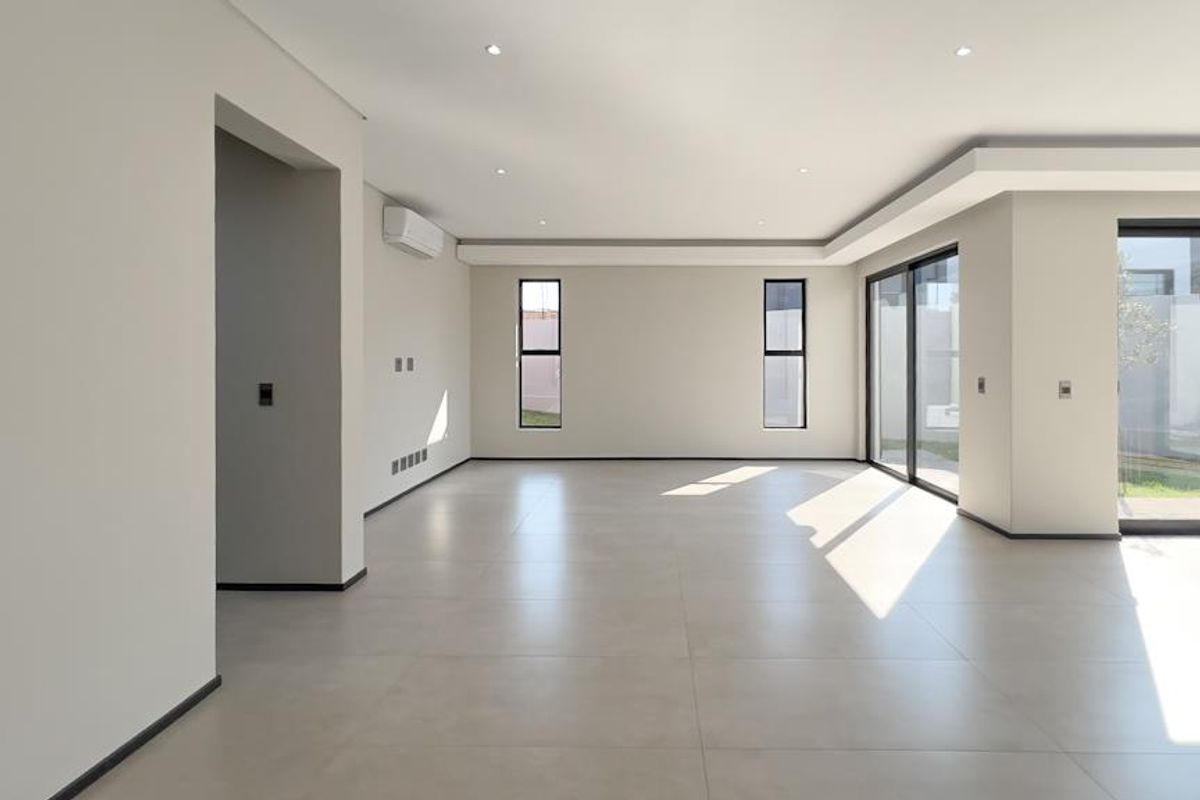 A bright, spacious, and modern open-plan living area featuring large format floor tiles, recessed lighting, and expansive sliding glass doors leading to the exterior.
