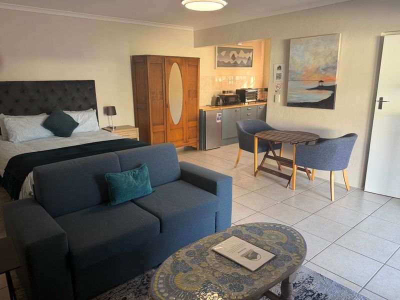 An open-plan studio apartment featuring a combined living, sleeping, and kitchenette area with tiled flooring throughout.