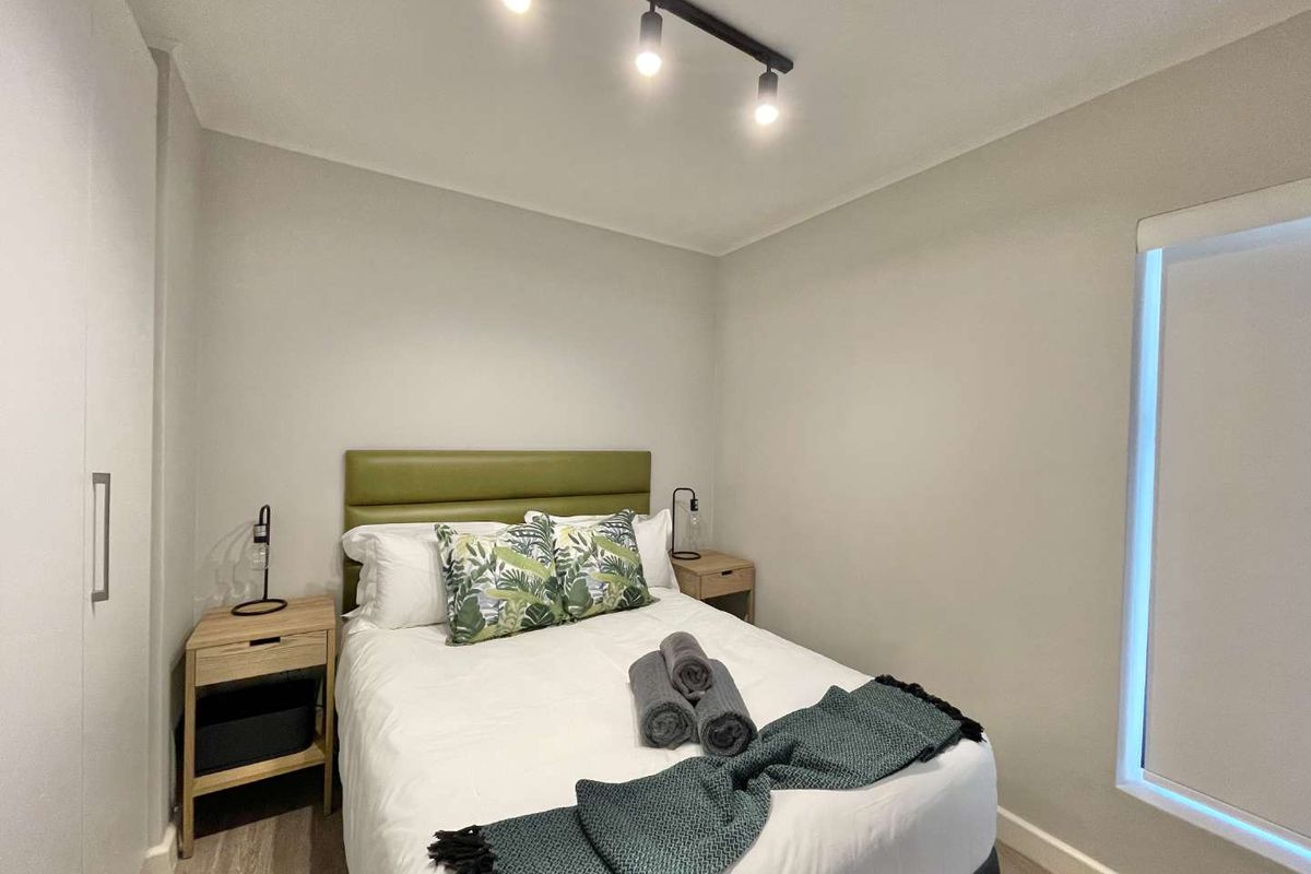 A well-maintained bedroom featuring built-in wardrobes, modern track lighting, and neutral finishes, creating a clean and functional living space.