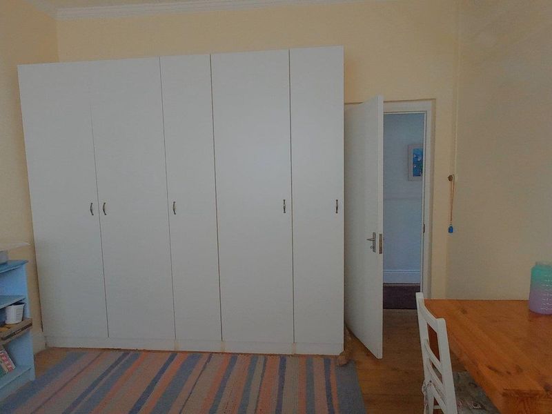 A bedroom featuring built-in wardrobes and timber flooring, offering a functional space with potential for modern updates.
