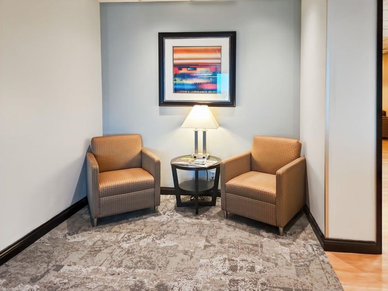 A small, well-maintained office seating area featuring neutral wall tones, patterned carpeting, and clean architectural finishes.