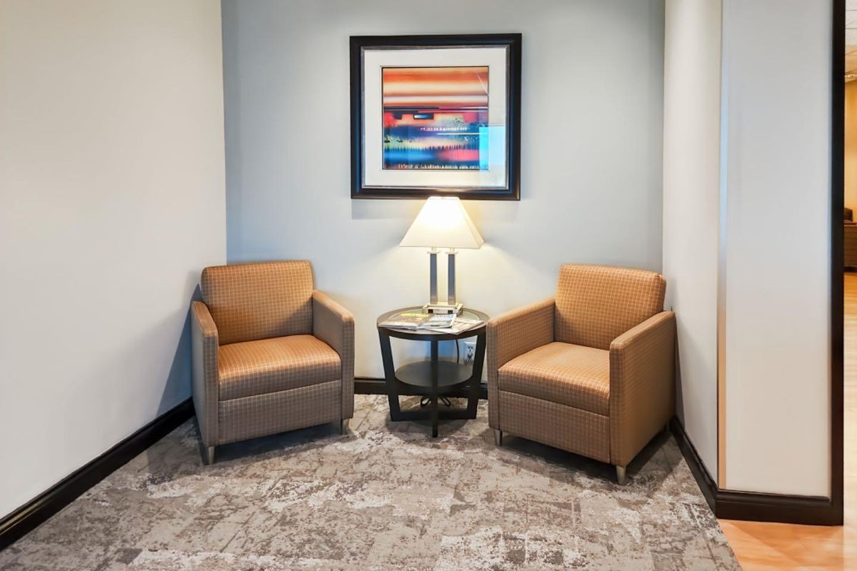 A small, well-maintained office seating area featuring neutral wall tones, patterned carpeting, and clean architectural finishes.
