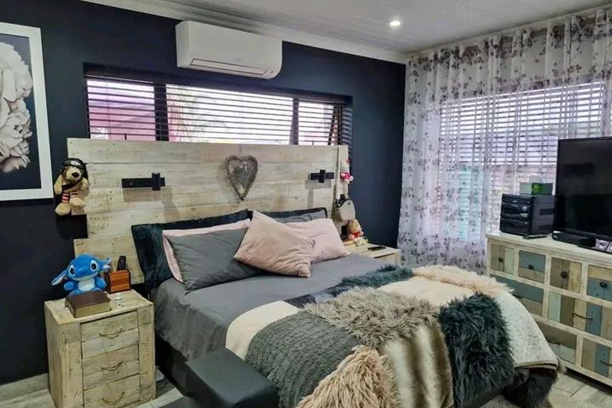 A well-maintained bedroom featuring dark accent walls, a split-system air conditioning unit, and horizontal window blinds.