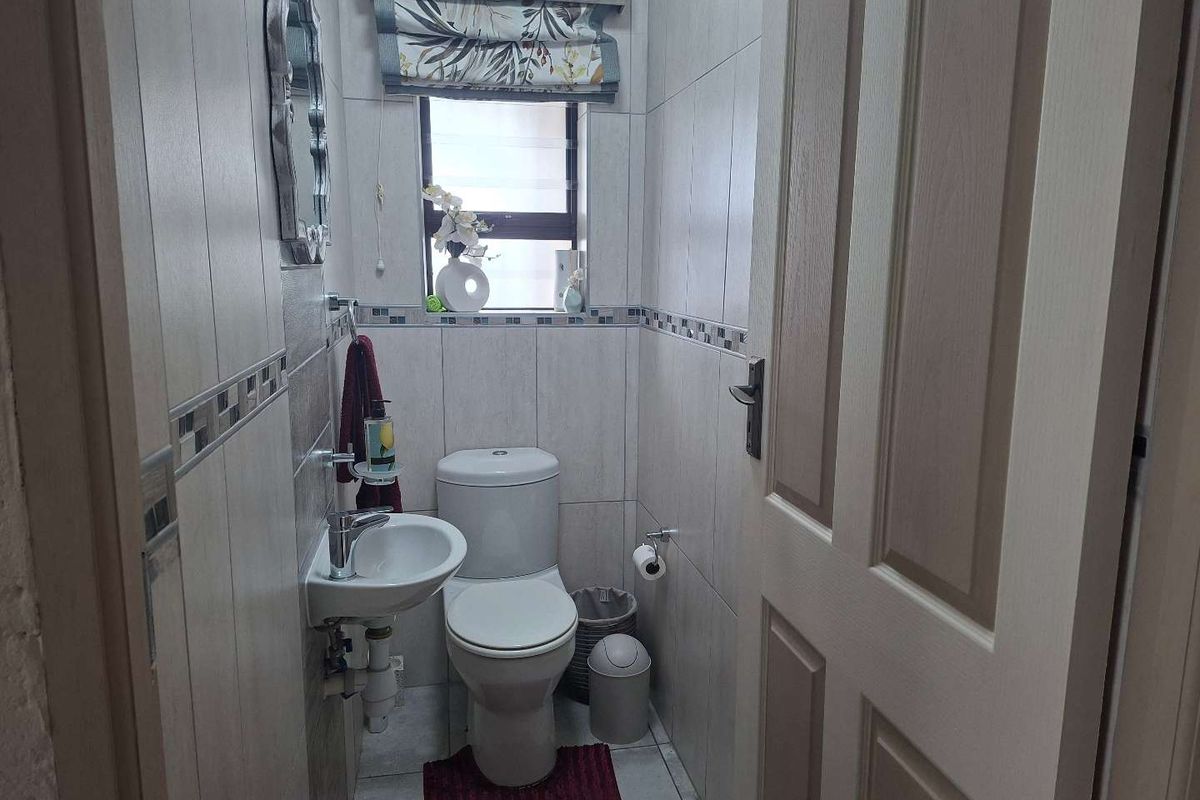 A compact, well-maintained guest bathroom featuring tiled walls, a wall-mounted basin, and a standard toilet.