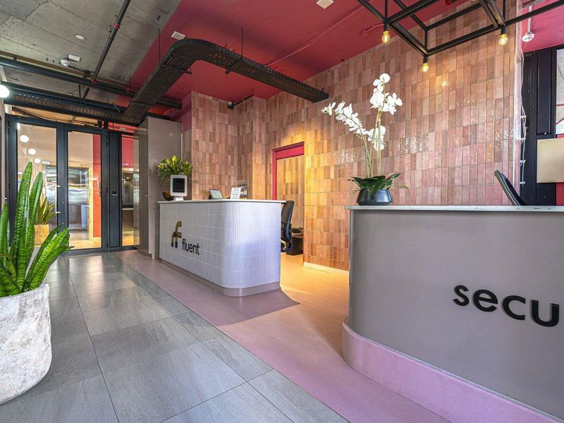Modern apartment building entrance lobby featuring a professional reception desk, contemporary tiled wall finishes, and an industrial-style exposed ceiling design.