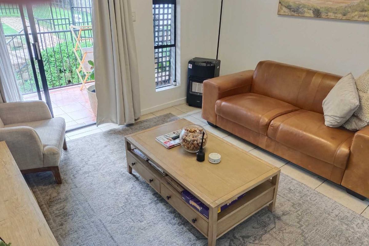 A bright living room featuring tiled flooring, a gas heater, and a sliding glass door providing access to an outdoor patio area.