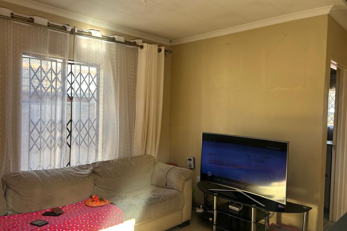 A living room featuring tiled flooring, security gate on the window, and standard ceiling finishes.