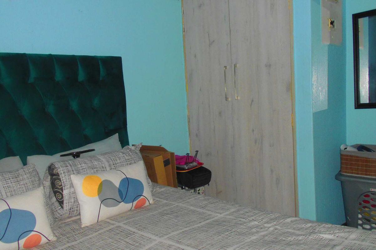 A bedroom featuring built-in wooden cupboards and a bright blue wall finish.
