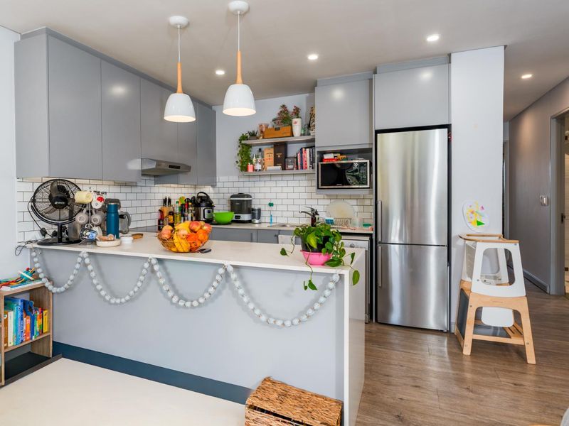 Modern kitchen featuring grey cabinetry, subway tile backsplash, stone countertops, and integrated appliances, creating a functional and stylish cooking space.