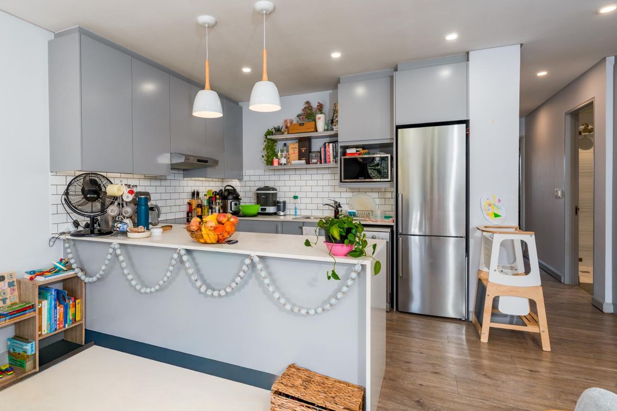 Modern kitchen featuring grey cabinetry, subway tile backsplash, stone countertops, and integrated appliances, creating a functional and stylish cooking space.