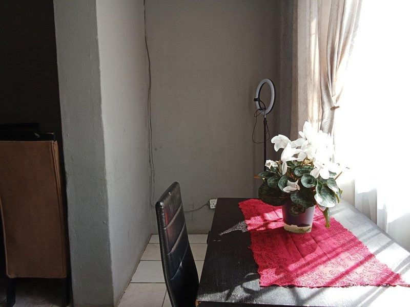 A simple dining area featuring tiled flooring and natural light from an adjacent window.