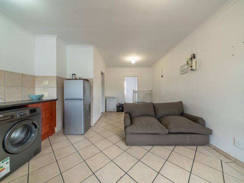 Open plan living area featuring tiled flooring, a compact kitchen section with cabinetry, and direct access to adjacent rooms.