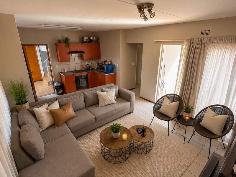 Open-plan living area featuring tiled floors, a compact kitchen with built-in cabinetry and appliances, and direct access to an outdoor space.