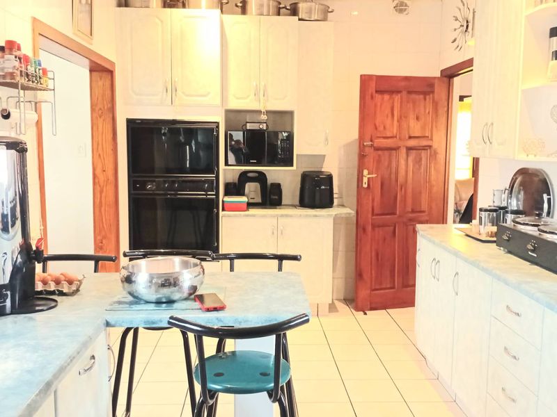 A functional kitchen featuring fitted cabinetry, built-in oven and microwave, laminate countertops, and tiled flooring with a traditional wooden door.