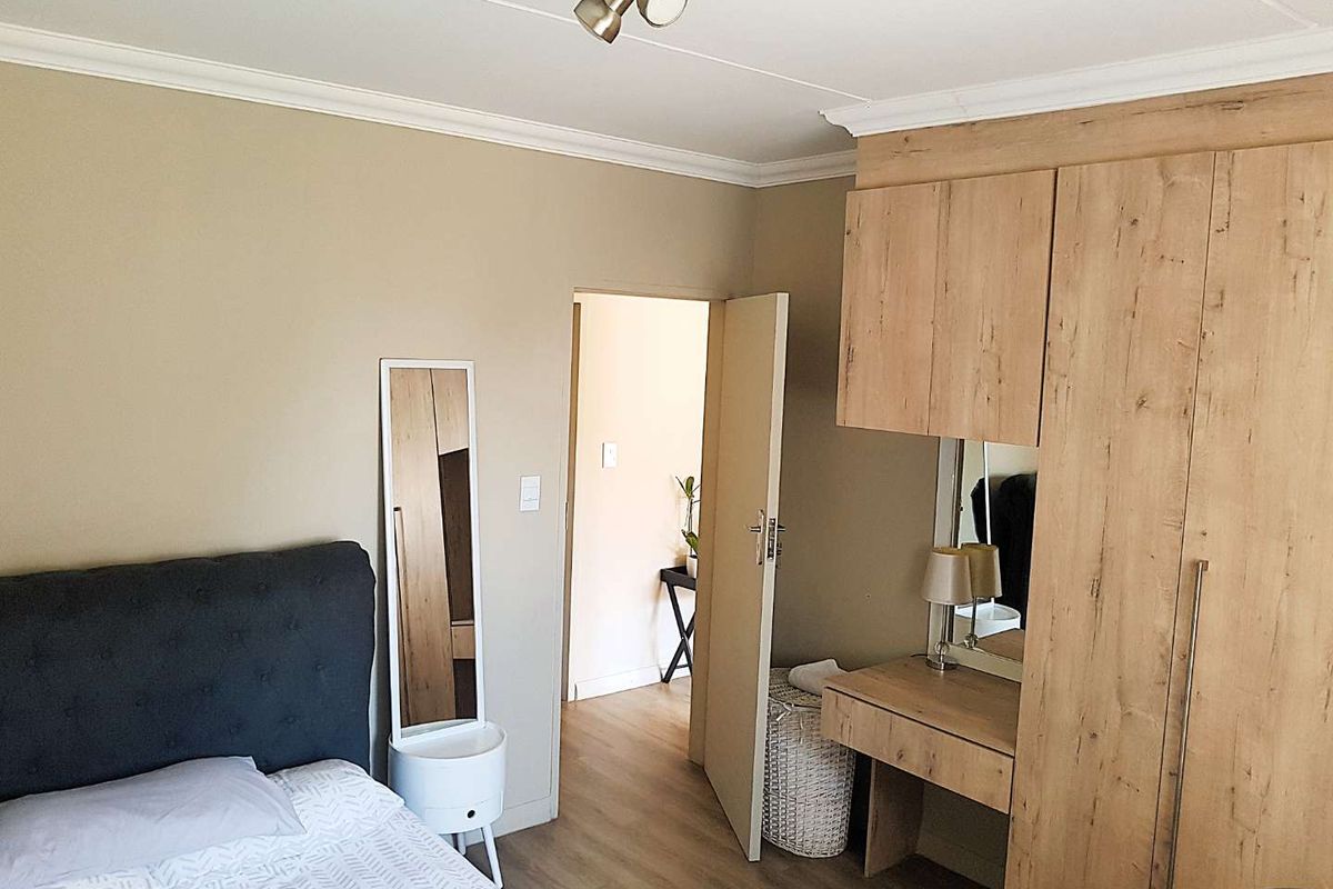 A well-maintained bedroom featuring built-in light wood cabinetry, a vanity area, and laminate flooring, providing a functional and organized living space.